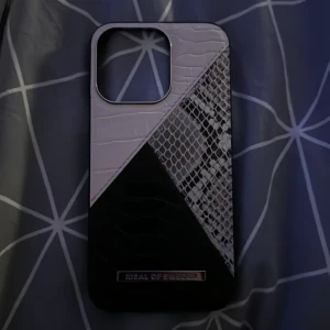 Mobilskal Night Sky Snake från IDEAL OF SWEDEN - Snyggt mobilskal för iPhone 13 Pro från IDEAL OF SWEDEN i modellen Night Sky Snake. Skalet har en cool design med ormmönster i svart och vitt, vilket ger en lyxig känsla. Perfekt för att skydda din mobil!