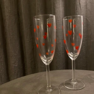 Champagneglas med röda hjärtan - Säljer två supersöta champagneglas dekorerade med röda hjärtan. Perfekta för romantiska tillfällen eller som en gullig present. 85kr/styck eller 2 för 150kr