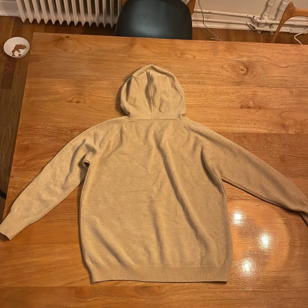 Säljer en mysig beige hoodie i merinoull . Perfekt för kyliga dagar. Den har långa ärmar och en praktisk huva med dragsko. Passar både till vardags och avslappnade tillfällen. Den är helt oanvänd.. Hoodies.