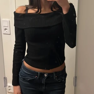 Svart offshoulder topp - Säljer en snygg svart offshoulder topp i ribbat material. Perfekt för både vardag och fest! Den har långa ärmar och en tight passform som framhäver figuren. Toppen är i mycket bra skick och passar perfekt till jeans eller kjol. Har bara använt 2-3 gånger