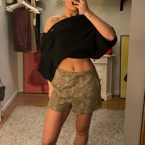 Ormmönstrade shorts - Säljer ett par snygga ormmönstrade shorts i beige och brunt. De är högmidjade och har en normal passform, perfekta för sommaren eller en utekväll. både bekväma och stiliga. Passar perfekt till en enkel topp eller en mer dressad look.