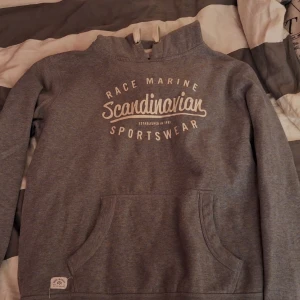 Grå hoodie från Race Marine - Säljer en grå hoodie från Race Marine med texten 'Scandinavian Sportswear' tryckt på framsidan. Den har en klassisk känguruficka och är perfekt för både vardag och chill. Superbekväm och stilren, passar till allt! 🖤