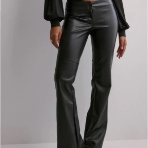 Svarta skinnbyxor - Snygga svarta skinnbyxor i bootcut-stil. De har en hög midja och stängs med knappar. Perfekta för en kväll ute eller en cool vardagslook. Passar bra till både klackar och sneakers.