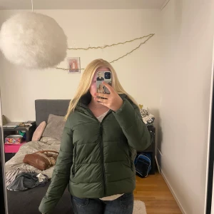Grön pufferjacka från Zara - Säljer en snygg grön pufferjacka från Zara. Jackan har en dragkedja framtill och en mysig huva. Den är i mycket bra skick. Storleken är M.