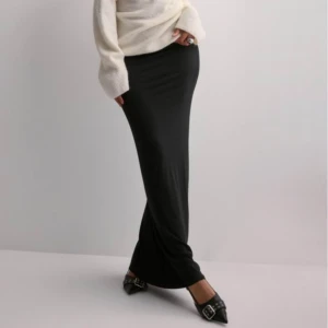 Svart långkjol - Snygg och elegant svart långkjol i ett mjukt och stretchigt material. Perfekt för både vardag och festliga tillfällen. Kjolen har en tight passform som framhäver figuren och är lätt att matcha med olika toppar och skor. Ett måste i garderoben för alla säsonger!