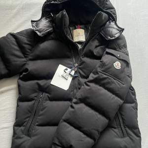 INTRSSEKOLL‼️Säljer en snygg svart pufferjacka från Moncler i mycket bra skick. Jackan har en dragkedja framtill och en praktisk huva. Perfekt för kalla vinterdagar och håller dig varm och stilren. Moncler-loggan syns på ärmen. Passar både till vardags och fest!🤩🤩