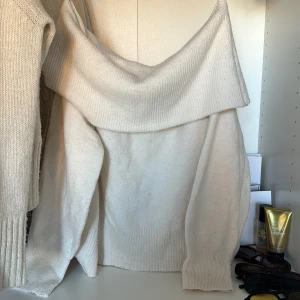 Vit offshoulder tröja från H&M - Säljer en superfin vit offshoulder tröja från H&M. Den är perfekt för både höst och vinter med sin mysiga och stilrena design. Tröjan har en ribbad kant vid axlarna som ger en snygg detalj. Köpt i våras!  Skulle säga att den e lite benvit
