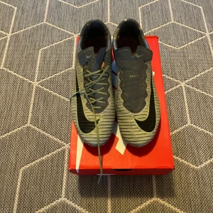 Nike Mercurial fotbollsskor - Säljer ett par grå Nike Mercurial fotbollsskor i bra skick. De saknar snören på ena skon. Perfekta för fotbollsträning eller match. Skorna är bekväma och ger bra grepp på planen. Skriv privat för fler bilder eller frågor