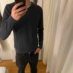 Mörkblå tröja från Dressmann - Säljer en snygg mörkblå tröja från Dressmann i Supima bomull. Den har en v-ringad hals och långa ärmar, perfekt för både vardag och lite finare tillfällen. Tröjan är i bra skick och superbekväm att ha på sig. Priset går möjligtvis att diskutera!