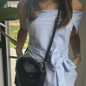 Svart väskband med Guld spänne - Väskbandet är svart och pryds av eleganta guldiga detaljer, inklusive spännet för att fästa bandet. Det är enkelt att justera längden efter egen önskemål. Våra väskband är självklart helt nya och aldrig använda!