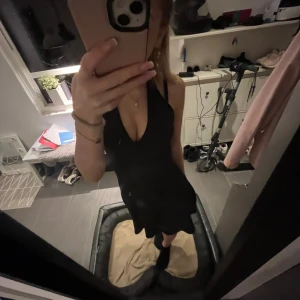 Svart klänning med halterneck och öppen rygg  - Säljer en elegant svart klänning med halterneck-design. Klänningen har en djup v-ringning öppen i ryggen och är perfekt för festliga tillfällen som tex nyår Den är i mycket bra skick 