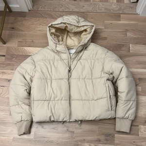 Beige pufferjacka från Monki - Säljer en supermysig beige pufferjacka från Monki i storlek S. Jackan har en praktisk huva och dragkedja framtill. Perfekt för kyliga höst- och vinterdagar. Den är i mycket bra skick och redo för nya äventyr! 🧥✨aldrig använd!