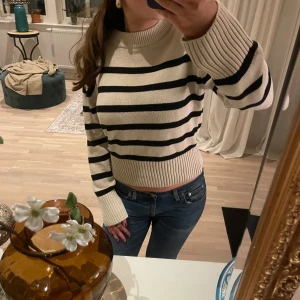 Randig tröja från Gina Tricot - Säljer en superfin randig tröja från Gina Tricot i storlek XS. Den är beige med svarta ränder och har en skön, ribbad kant vid ärmslut och nederkant. Perfekt för både höst och vår! 🖤🤍