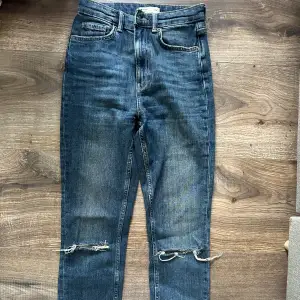 Säljer ett par snygga blå jeans från gina tricot i storlek 34. De är högmidjade och har slitna detaljer vid knäna för en trendig look. 🕺