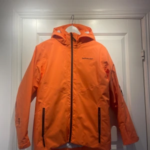 Orange skidjacka från Peak Performance - Säljer en snygg orange jacka från Peak Performance. Den har en huva och dragkedja framtill samt praktiska fickor med dragkedjor. Har används en säsong i skidbacken.             Priset går att diskutera.                                   Storlek: 170.                                                        Nypris: 3000 kr. 