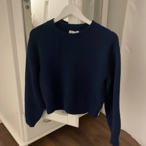 Mörkblå stickad tröja från & Other Stories - Säljer en superfin mörkblå stickad tröja från & Other Stories. Den är i storlek S och har en croppad passform som är perfekt för både höst och vinter. Tröjan har långa ärmar och en klassisk rund halsringning. Perfekt för att hålla sig varm och stilren! 💙