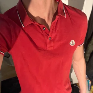 Röd pikétröja från Moncler - Snygg röd pikétröja från Moncler med klassisk krage och knappar. Skick 7/10 men inga större defekter. Köpte pikén på en second hand och har knappt använt den. 