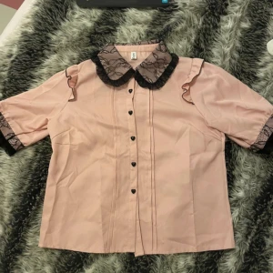 Jirai kei blus  - rosa jirai kei blus. Har söta svarta spetsdetaljer och hjärtknappar. Den har en liten fläck (sista bilden) men kommer förmodligen att försvinna i tvätten. Har bara använt den en gång .💕