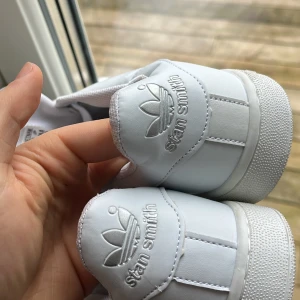 Vita Adidas Stan Smith sneakers - Säljer ett par klassiska vita Adidas Stan Smith sneakers. Skorna har en stilren design med snörning och perforerade detaljer på sidorna. Perfekta för en avslappnad och trendig look. Köptes i affär för 999kr men dröjer dom för 550kr för vill bara bli av med dom :)