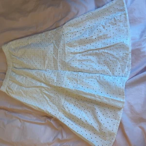 Vit kjol med broderade detaljer - Charmig vit kjol med broderade hålmönster och elastisk midja. Perfekt för en somrig look med sin luftiga design och fina detaljer. Pris kan diskuteras 
