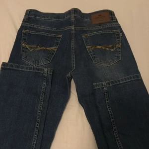 Mörkblå jeansbyxor från Paul Kane - Snygga mörkblå jeansbyxor från Paul Kane med klassisk femficksdesign och kontrastsömmar på bakfickorna. Byxorna har en knapp och dragkedja framtill.