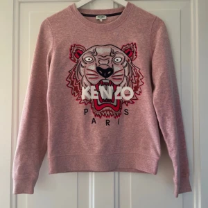 Rosa sweatshirt från Kenzo - Säljer en rosa sweatshirt från Kenzo med ett stort tigerhuvud och texten 'KENZO PARIS' broderat på framsidan. Tröjan har långa ärmar och en rund halsringning.