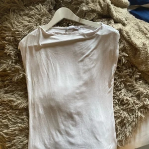 Vit ärmlös topp från 157 - Säljer en stilren vit ärmlös topp från 157. Perfekt för varma dagar eller som ett basplagg i garderoben. Toppen har en enkel design med rund halsringning.