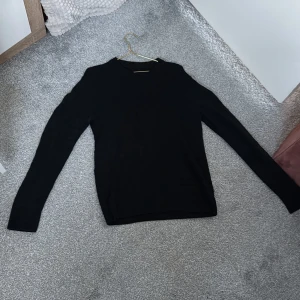 Svart tröja från Hugo Boss - Snygg svart tröja från Hugo Boss med diskret mönster. Tröjan har långa ärmar och en klassisk passform. Perfekt för en stilren look.