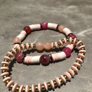 Färgglada armband med pärlor - Två stiliga armband med pärlor i rosa, vita och guldiga nyanser. Armbanden har en mix av runda och platta pärlor som ger en lekfull och trendig look. Perfekt för att addera lite färg och stil till din outfit. Båda för 100 kr en för 50kr