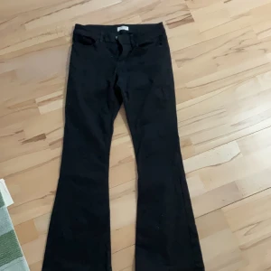 Svarta byxor från Lindex - Snygga svarta byxor från Lindex med bootcut-stil. Perfekta för en stilren look. Byxorna har en klassisk design med dragkedja och knapp framtill.