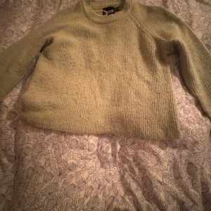 Grön stickad tröja från Pieces - Mysig grön stickad tröja från Pieces. Den har en rund halsringning och långa ärmar, perfekt för kyligare dagar. Tröjan har en enkel och stilren design som passar till många olika outfits. 