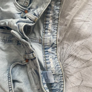 Ljusa jeans med slitningar - Säljer ett par ljusa jeans med slitningar på knäna. De har en regular fit och är högmidjade. Perfekta för en avslappnad stil. Jeansen har klassiska fem fickor och knappgylf.