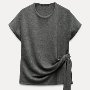 Grå topp med knyt från Zara - Intressekoll! Säljer en stilren grå topp från Zara med korta ärmar och en snygg knytdetalj på sidan. Perfekt för en avslappnad men chic look. Skriv för frågor! Priset kan absolut diskuteras 