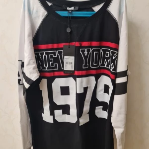 Svart och vit långärmad tröja med New York 1979 tryck - Cool långärmad tröja från Bikbok i svart och vitt med ett stort tryck av 'New York 1979' i vitt och rött. Perfekt för en avslappnad stil. Tröjan har en normal passform och är gjord i mjukt bomullsmaterial. Helt ny med prislapp kvar.