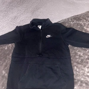 Svart fleece hoodie från Nike - Säljer en svart fleece hoodie från Nike i storlek S. Den har en halv dragkedja och en praktisk magficka. Perfekt för kyliga dagar och har en stilren design med Nike-loggan på bröstet. Supermysig och varm!