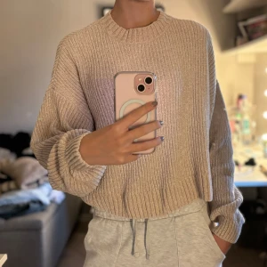 Beige stickad tröja från Divided - Säljer en supermysig beige stickad tröja från Divided. Den har en normal passform med långa ärmar och ribbade detaljer vid hals, ärmslut och nederkant. Perfekt för höst och vinter när du vill hålla dig varm och stilren. Tröjan är i nyskick och redo för en ny ägare!