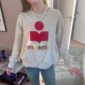 Grå sweatshirt från Isabel Marant - Säljer en grå sweatshirt från Isabel Marant med ett stort rött och färgglatt tryck på framsidan. Tröjan har en avslappnad passform och långa ärmar. Perfekt för en casual look!