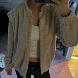 teddyjacka - Mysig beige teddyjacka med knappar framtill. Perfekt för kyliga dagar när du vill hålla dig varm och bekväm. Jackan har en avslappnad passform och långa ärmar. Står storlek L på jackan men jag skulle säga att det mer är en S