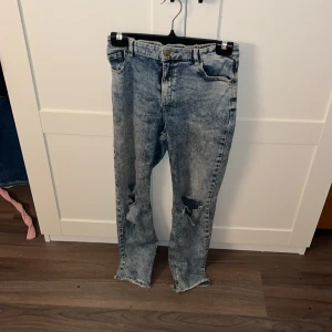 Blå jeans från Lindex - Säljer ett par blå jeans från Lindex med slitna detaljer på benen. 