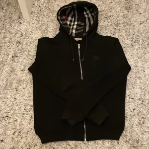 Svart Burberry kofta  - Säljer en stilren svart Burberry kofta, har bara använt den ungefär 1-2 månader. Jättebra skick och håller dig varm. Köpte den för 1100 kr säljer nu den för 849 kr. Koftan är i stolek S, det står M men är liten i storleken. Hör av er folket! 