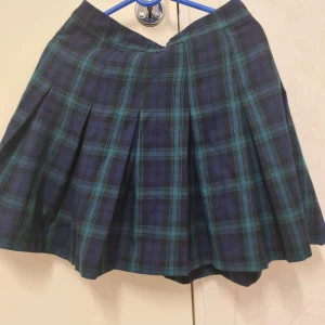 Blå och grön rutig kjol - Söt blå och grön rutig kortkjol med veckad design. Tillverkad i en blandning av polyester och viskos för en bekväm passform. Sparsamt använt. Sitter för tajt på mig nu. 