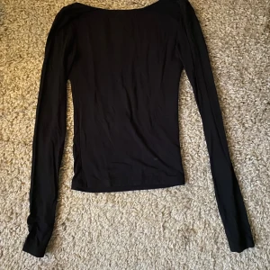 Svart långärmad topp från Gina Tricot - Säljer en stilren svart långärmad topp från Gina Tricot. Den är öppen i ryggen och och har en stilren look. Storleken är XXS men funkar som XS. Säljer pga att den inte kommer till användning. 