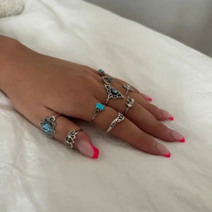 Set med silverringar med turkosa stenar - Snyggt set med flera silverringar, dekorerade med turkosa stenar och detaljerade mönster. Perfekt för att ge en bohemisk touch till din stil. Ringarna har olika storlekar och design, vilket gör dem lätta att kombinera.
