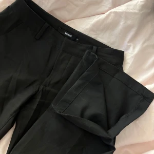 Svarta kostymbyxor från BikBok - Snygga svarta kostymbyxor från BikBok i storlek 34. Byxorna är lågmidjade med fickor framtill 