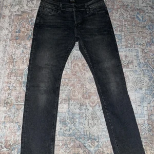 Svarta jeans från Jack & Jones - Snygga svarta jeans från Jack & Jones med en klassisk femficksdesign. De har en knappgylf och är i en rak passform som passar perfekt till vardags. Jeansen är tillverkade i ett slitstarkt material som ger en bekväm känsla hela dagen.W31 L32