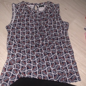 Mönstrad ärmlös topp från Stockh LM - Snygg ärmlös topp från Stockh LM med ett unikt mönster i marinblått, vitt och orange. Perfekt för en stilren look. Toppen har en rund halsringning och knytning i nacken. Storlek S men är ganska stretchig så M och kanske till och med L skulle nog kunnas ta på sig denna