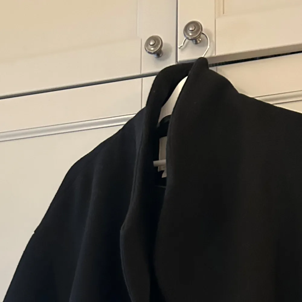 Elegant svart kappa från hm med en stilren design. Omlottvariany med skärp i midjan och lite större slag. Knälång. Inga större anmärkningar, i gott skick.. Takit.