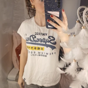 Vit t-shirt från Superdry - Säljer en vit t-shirt från Superdry med tryck. T-shirten är i storleken EU 40 men passar bra på mig som brukar ha xs/s💕