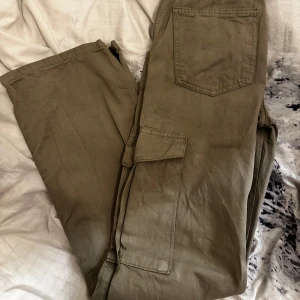 Olivgröna cargobyxor från Pull&Bear - Säljer ett par olivgröna cargobyxor från Pull&Bear. Byxorna har flera praktiska fickor och en avslappnad passform. Perfekta för en casual look. Sista bilden så är det lite målarfärg som har kommit på byxorna men syns knappt! 🩷