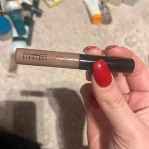 MAC Lipglass i nude nyans - Säljer en MAC Lipglass i en snygg nude nyans. Perfekt för att ge läpparna en glansig finish med en hint av färg. Kompakt och lätt att ta med i väskan. Nytt